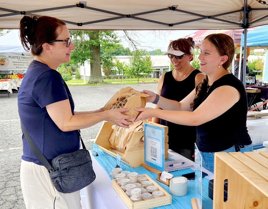 Farmers' Market vendor handing goods to customer